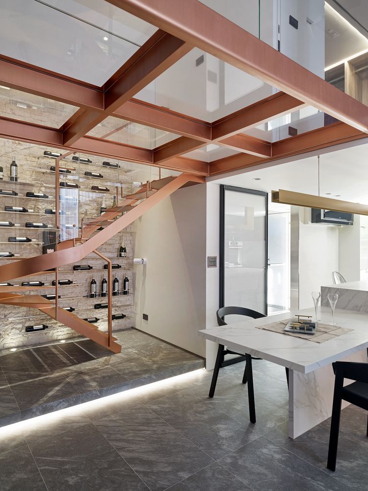 Behind the staircase is a gorgeous accent wall with horizontal wine racks and accent lighting