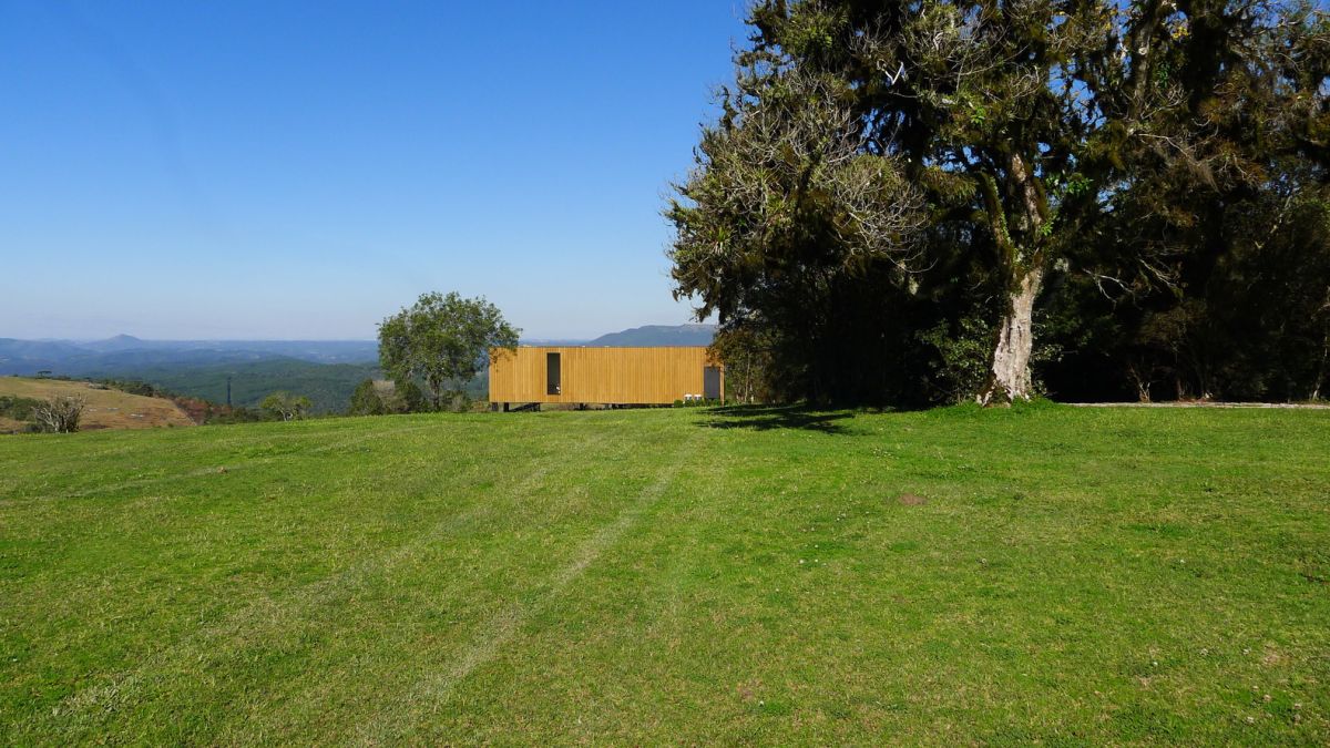 A vast green area unfolds around the cabin, ensuring unobstructed views towards the distant mountain range