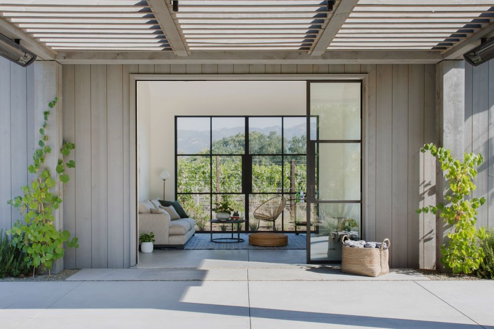 The living area features glazed doors which open up and connect the space to a large covered patio