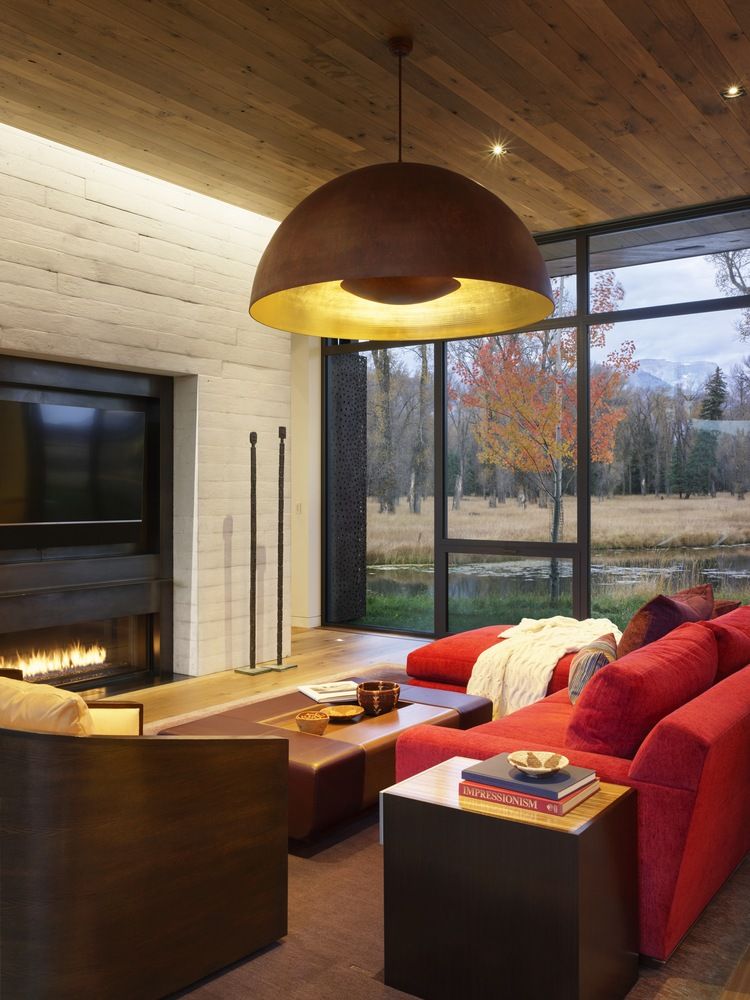 Inside the main volume of the pavilion, the kitchen sits on one side and a large fireplace on the other
