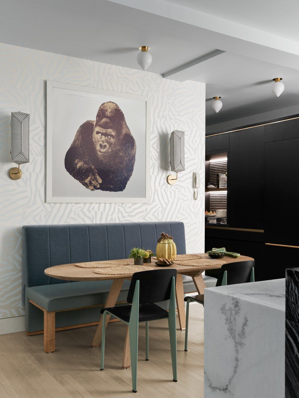 A cozy breakfast nook was set up in the kitchen. It has an oval table, an upholstered bench and two simple chairs