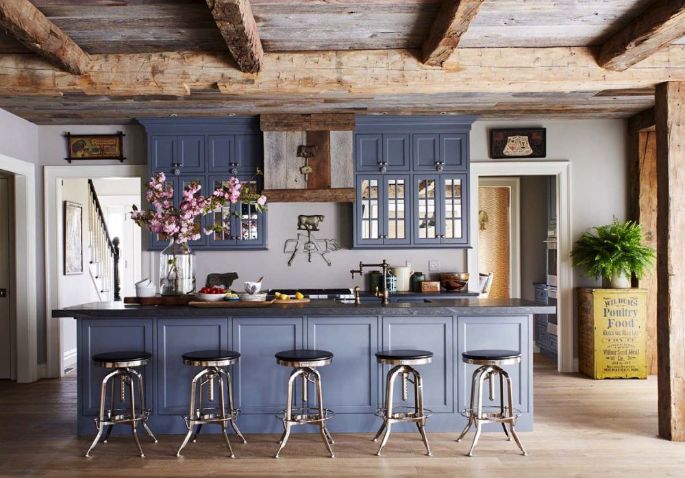 The open space kitchen features a large island which doubles as a bar, complemented by five simple bar stools