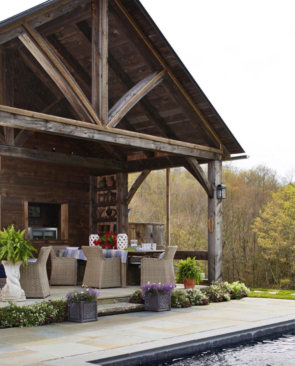 The house features a covered porch on one side, with an outdoor kitchen and comfortable furniture