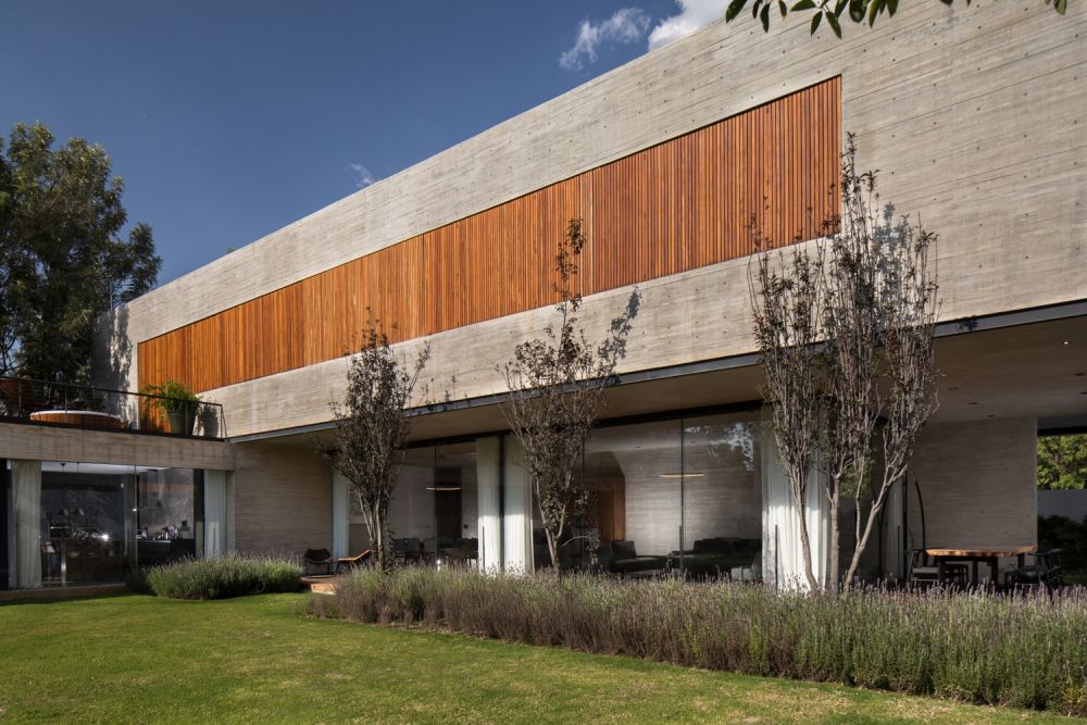 The closed wooden shutters sit flush with the outer concrete facade, giving the house a minimalist appearance