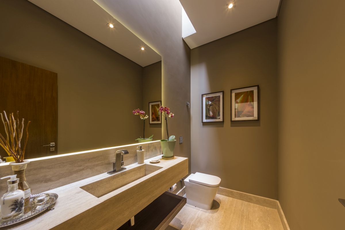 A huge backlit wall mirror enlarges the bathroom visually while also highlighting its beautiful colors