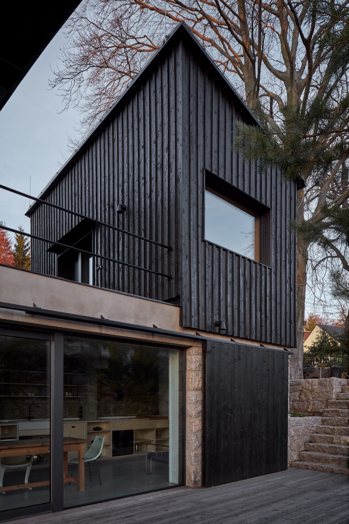 The dark exterior of the new volumes contrasts with the stone below