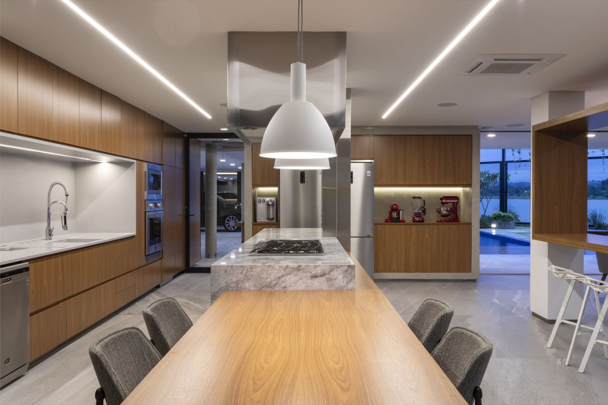 The kitchen island extends into a dining table, with minimalist pendant lamps hanging from the ceiling