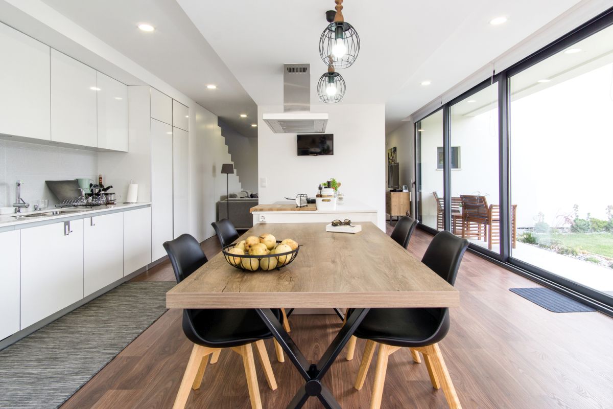 The kitchen and dining area seamlessly merge into one, with a clear distinction in the type of flooring 