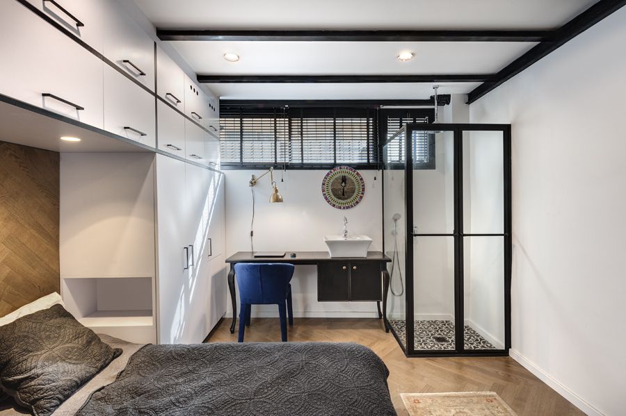 The bedroom has a clear shower area in one of its corners, with a sink table/ desk next to it