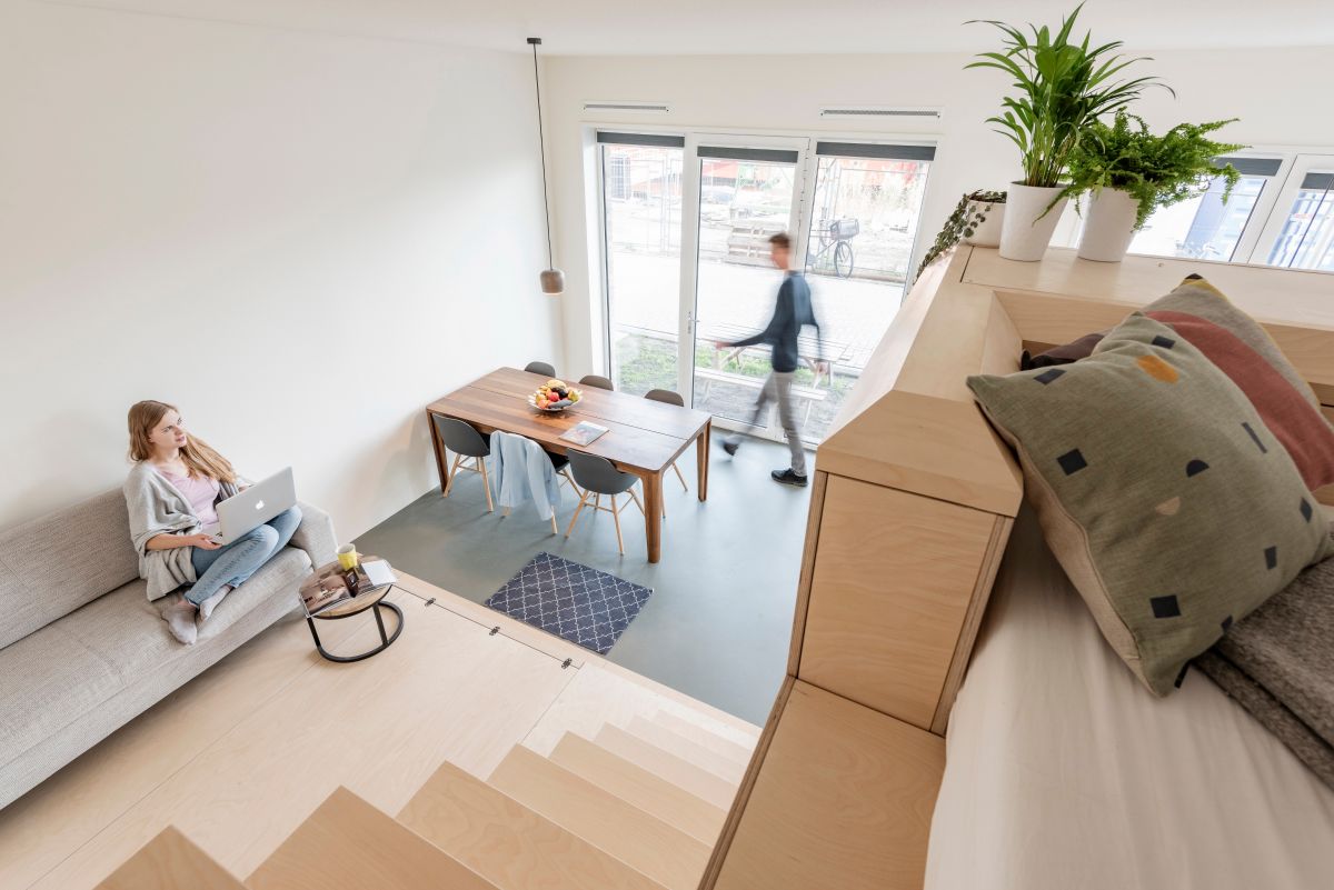 The sofa is placed on a platform, facing the staircase and the dining area is on its left side