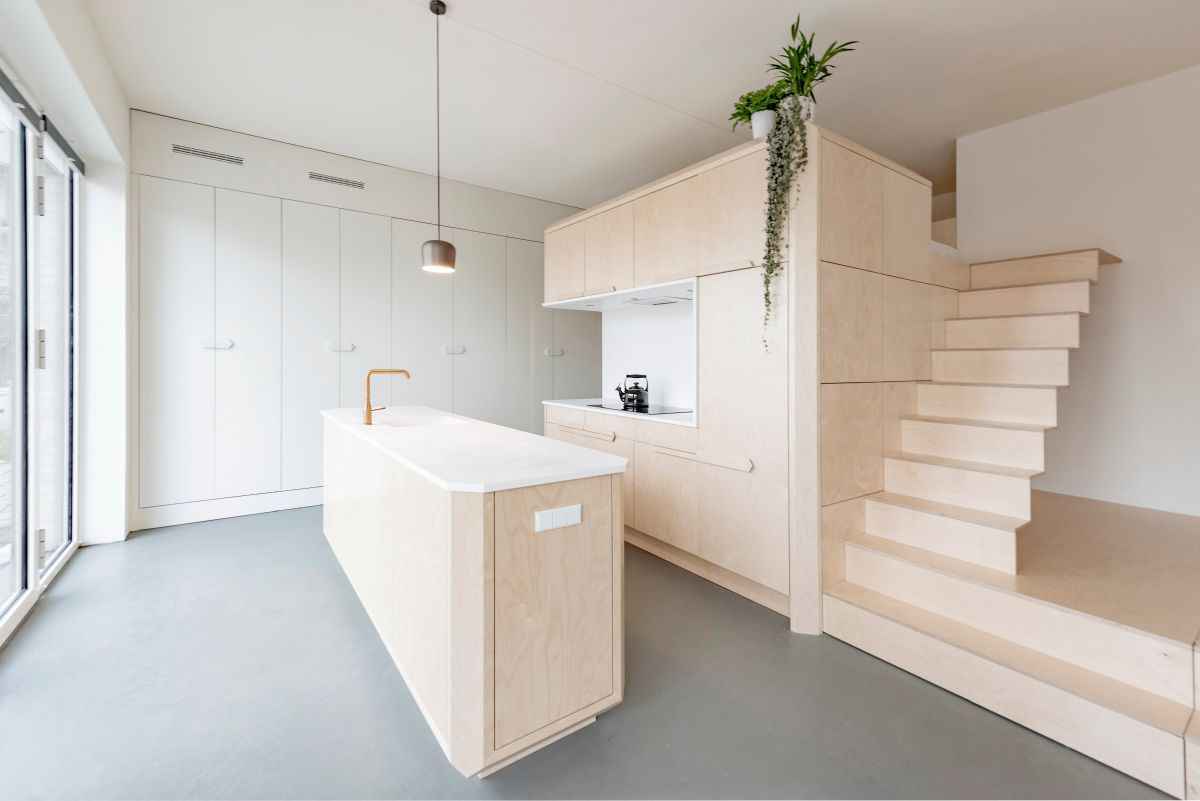 The kitchen island matches the storage unit and loft bed area, maintaining a harmonious aesthetic
