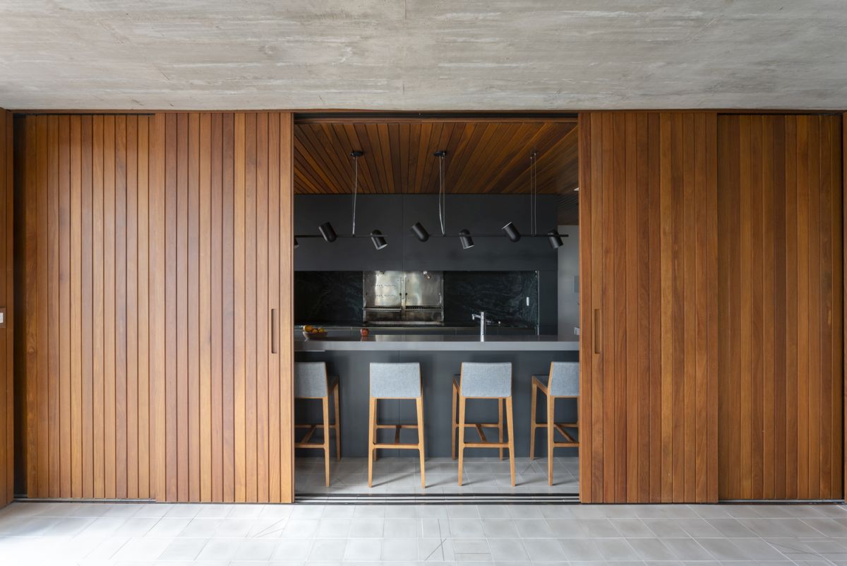 Sliding wooden panels can easily conceal the kitchen, separating it from the living area