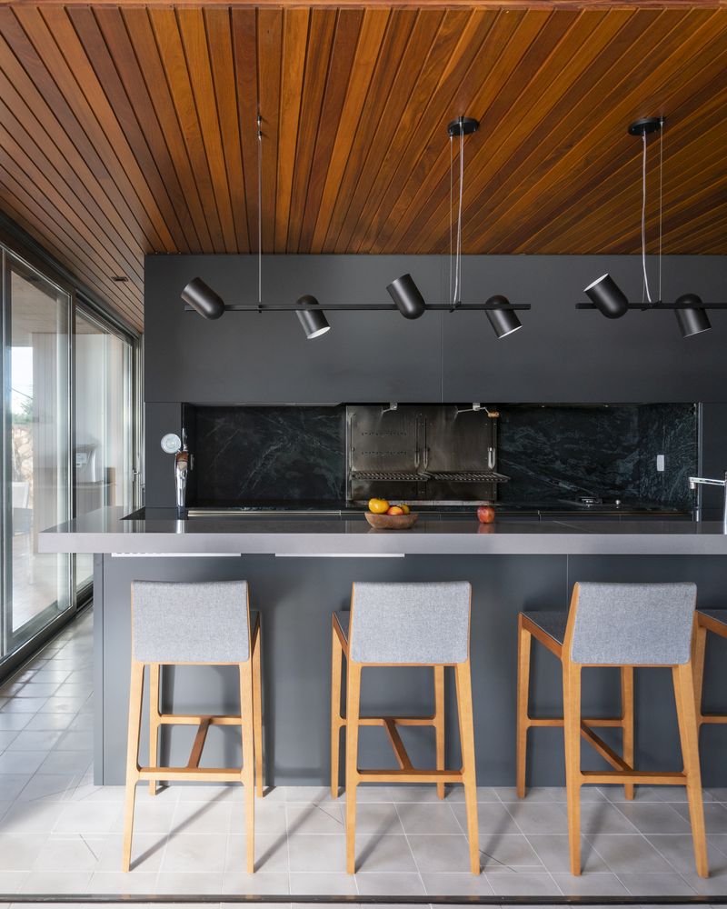 The kitchen is almost entirely grey, with minimalist furniture and a beautiful wooden ceiling