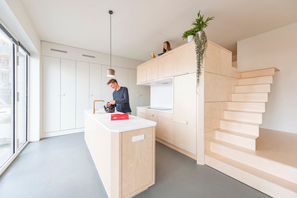 The kitchen and loft bed are merged into a single large unit built out of birch wood