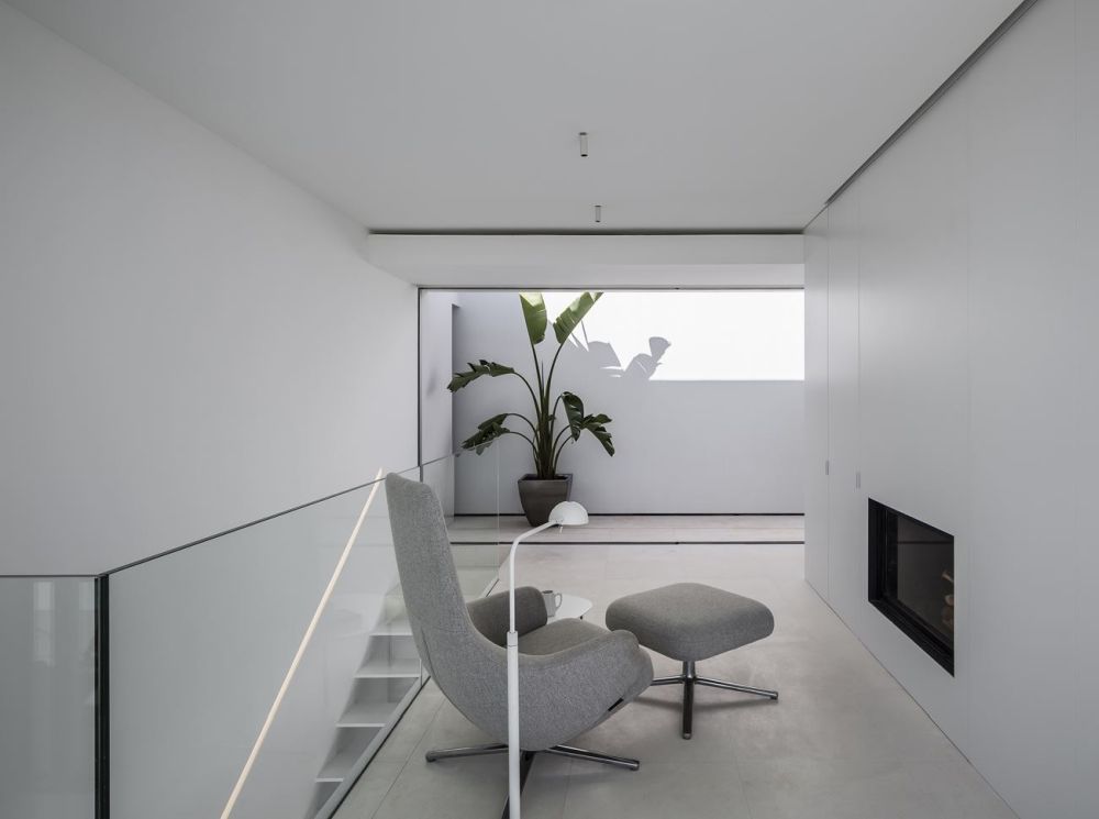 The interior design is minimalistic, with clean white walls, ceilings and concrete flooring throughout the house