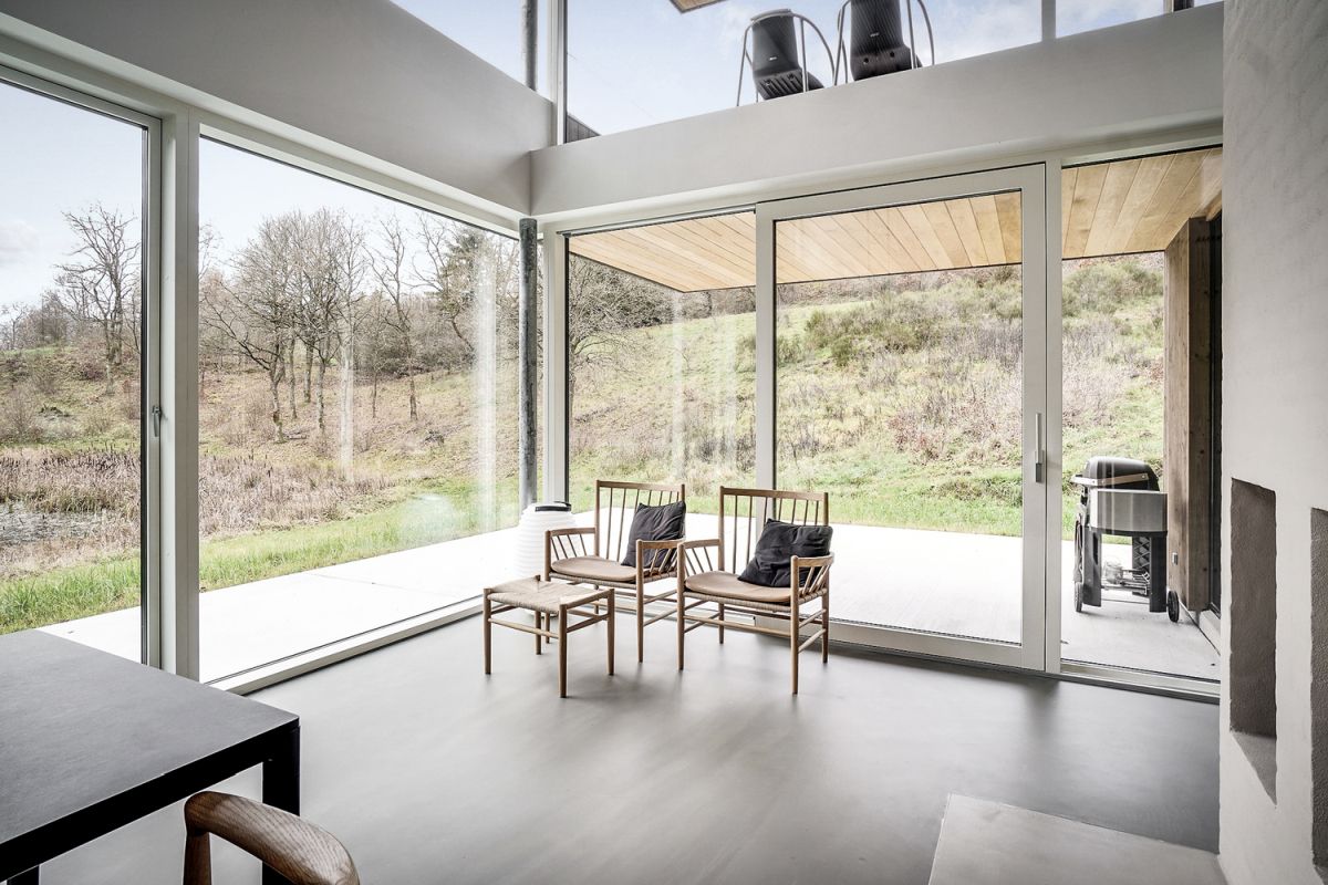 The dining area is a double-height space with huge windows and a connection to the covered deck