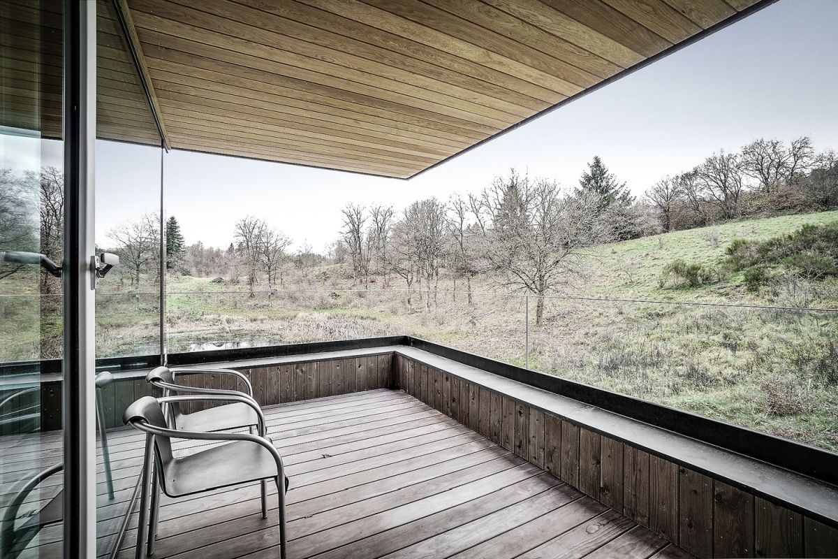 Glass doors connect the living spaces to a covered terrace with panoramic views of the surroundings