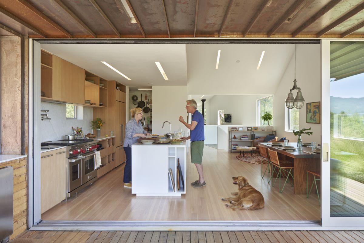 The indoor kitchen extends outside under a cantilevered eave