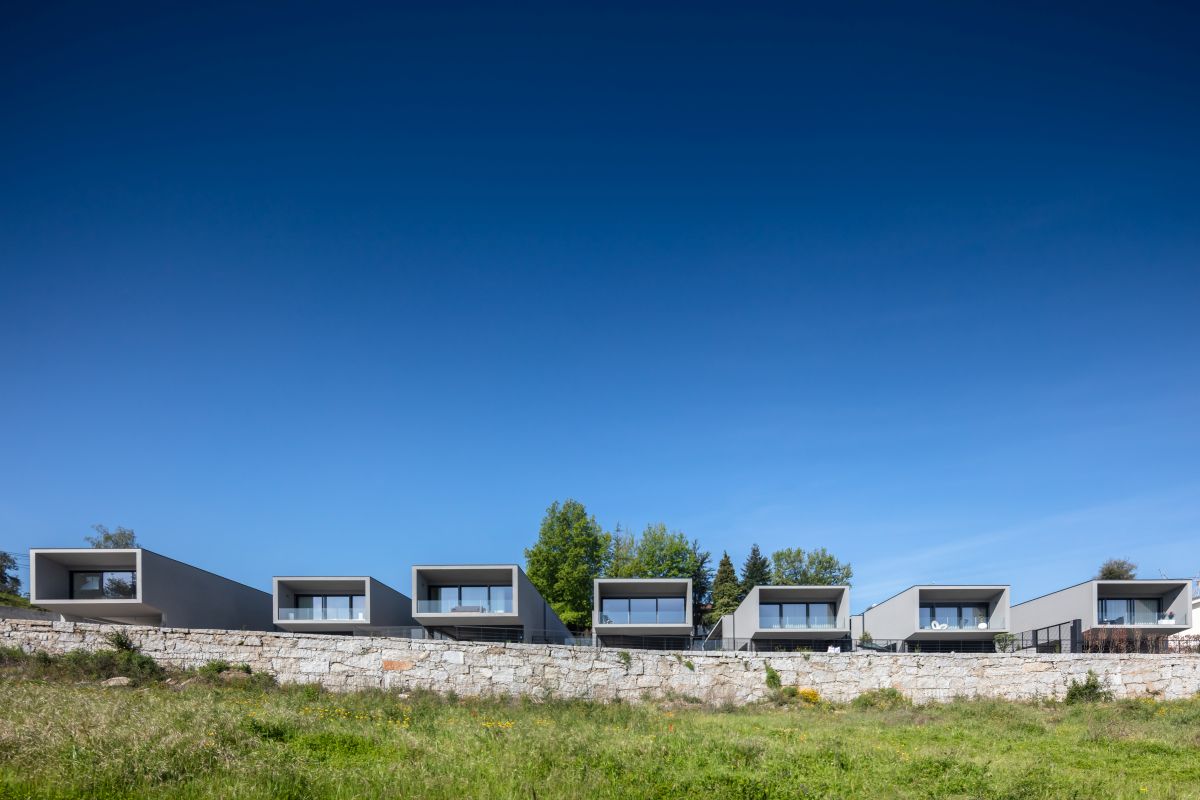 The houses are all parallel to each other and oriented towards the open land in the distance