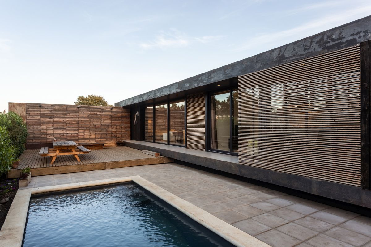 An inner courtyard is sheltered by a wall wood-covered wall and by vegetation