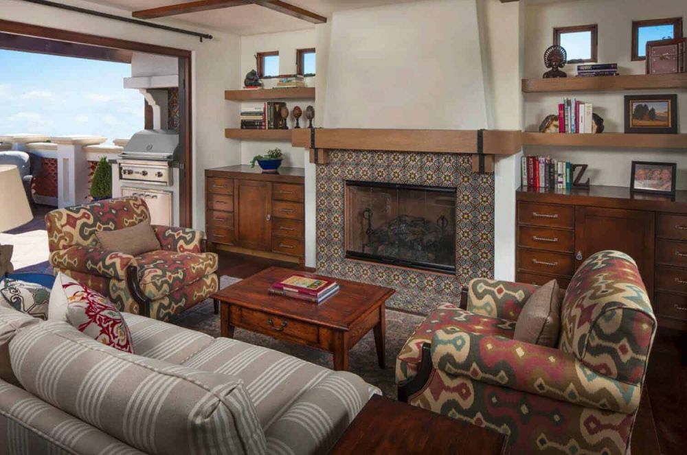 The covered outdoor living room is super cozy, with comfortable armchairs and a fireplace
