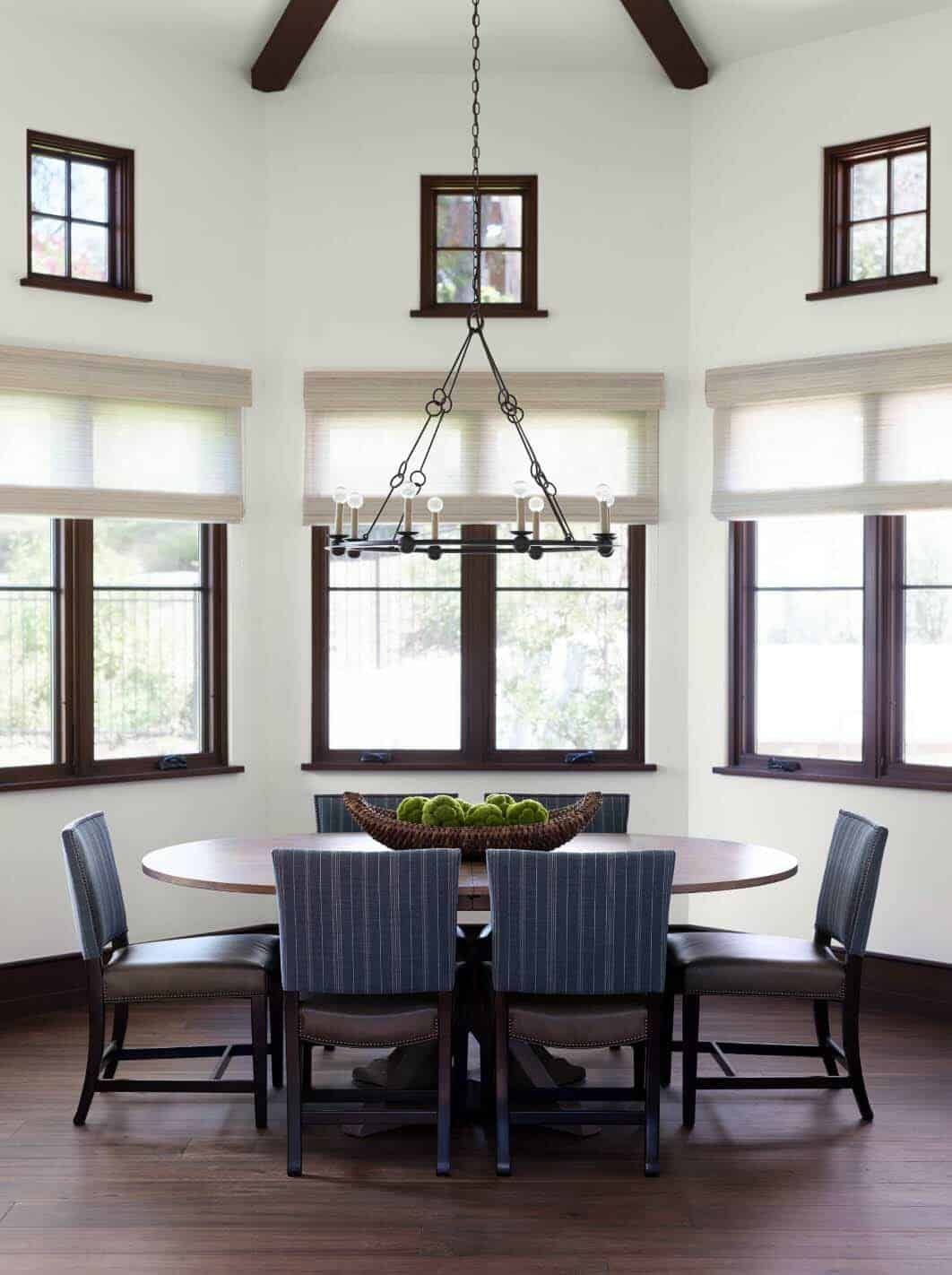The dining room is framed by windows and has a circular wooden table with leather chairs all around