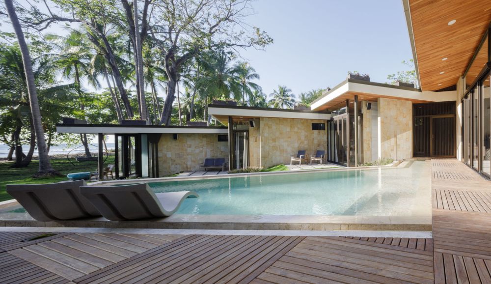 The swimming pool is framed by a wooden terrace that acts as a buffer between it and the houses