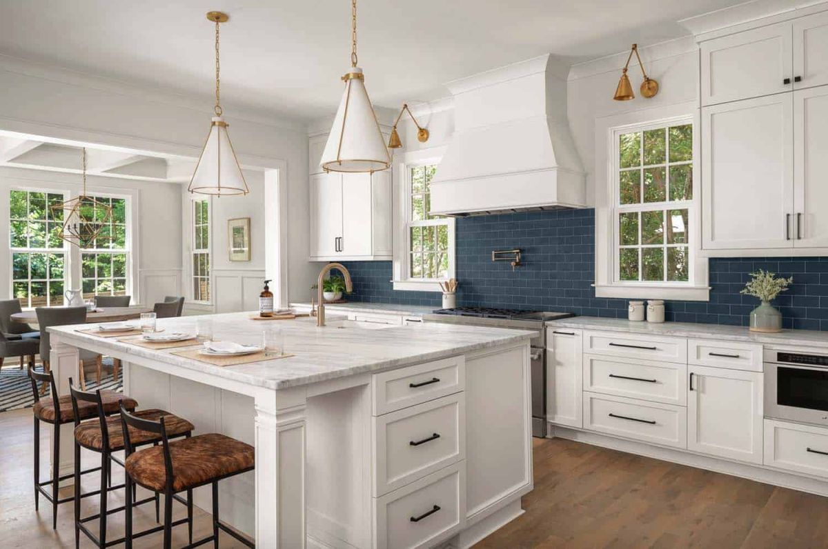 The island has a built-in sink and a white marble top. One side serves as a bar or breakfast table