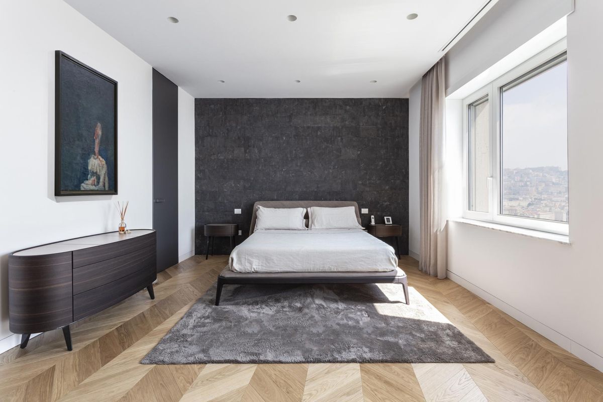 The master bedroom has a herringbone parquet floor and white walls which emphasize the contemporary nature of the design