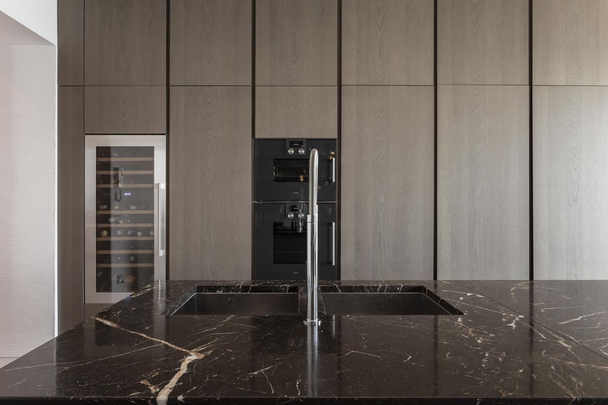 The black Carrara marble kitchen island goes well with the dark oak furniture