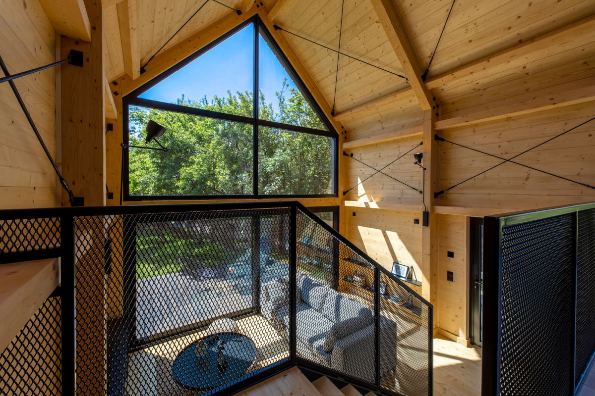 The living room has a double-height ceiling, with windows that go all the way up