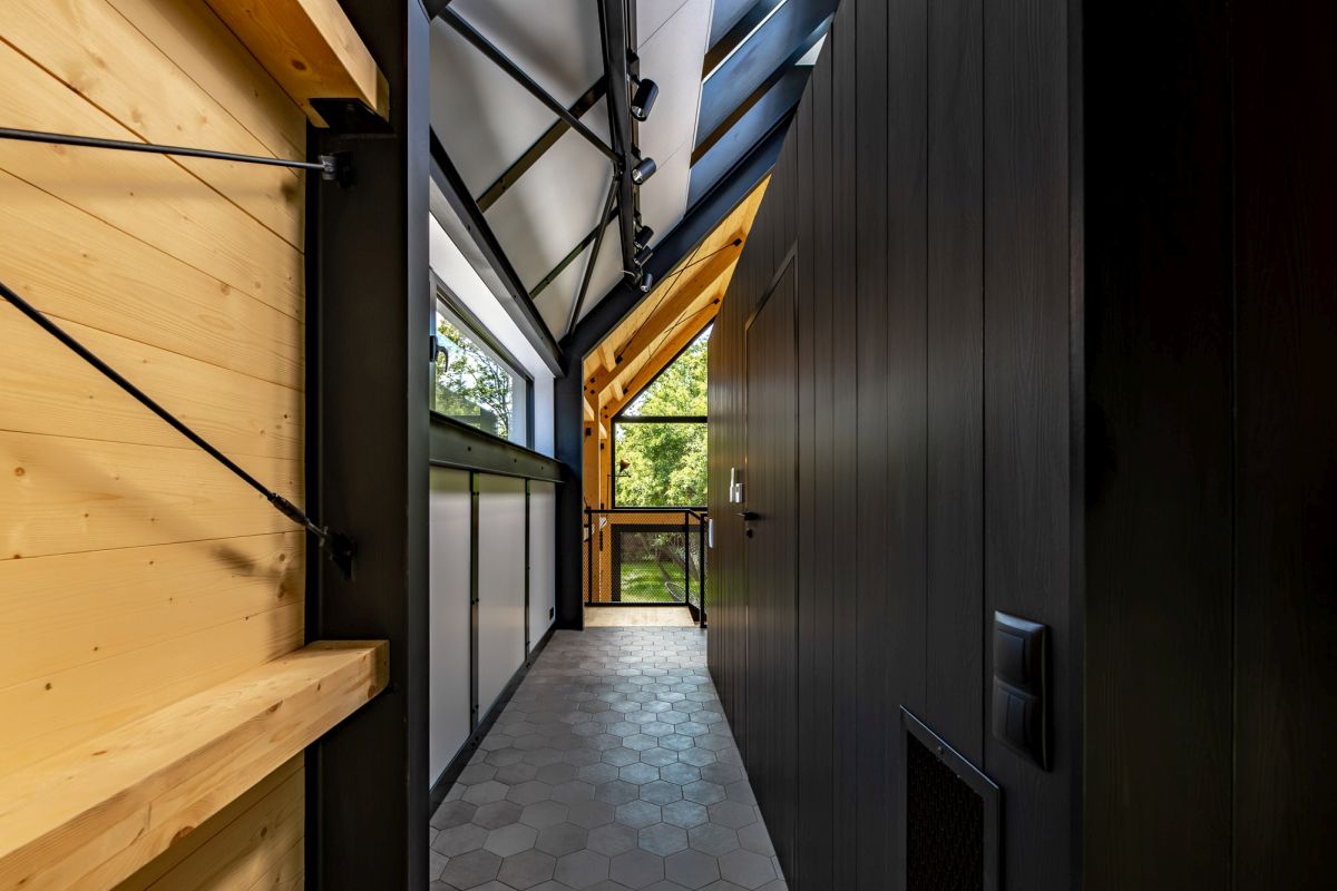 The interior design is defined by extensive black surfaces complemented by natural wood and large windows