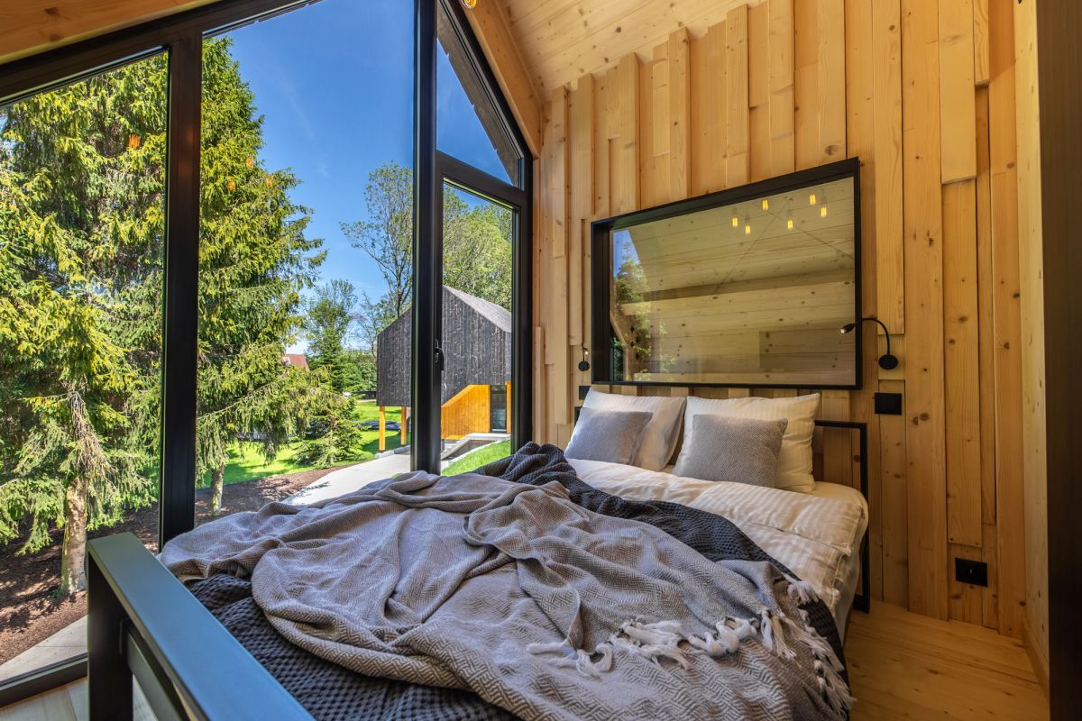 The walls, floor and ceiling of the bedroom are covered in wood and that creates a very cozy and inviting ambiance