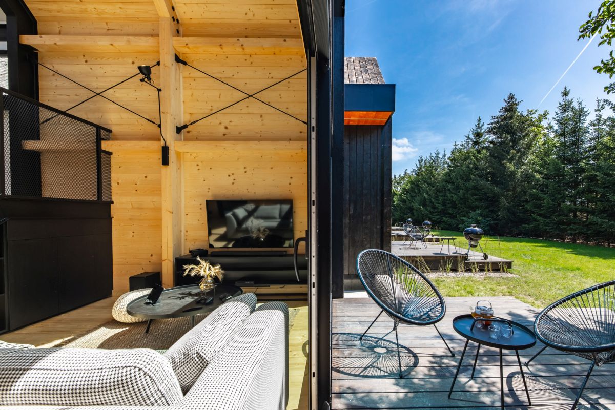 A large sliding door connects to living area to an outdoor terrace which overlooks the forest