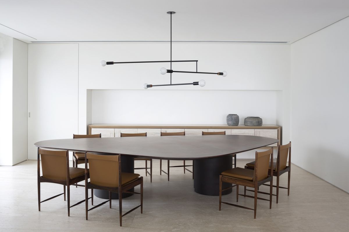 The dining table is very large and surrounded by eight elegant and comfortable chairs