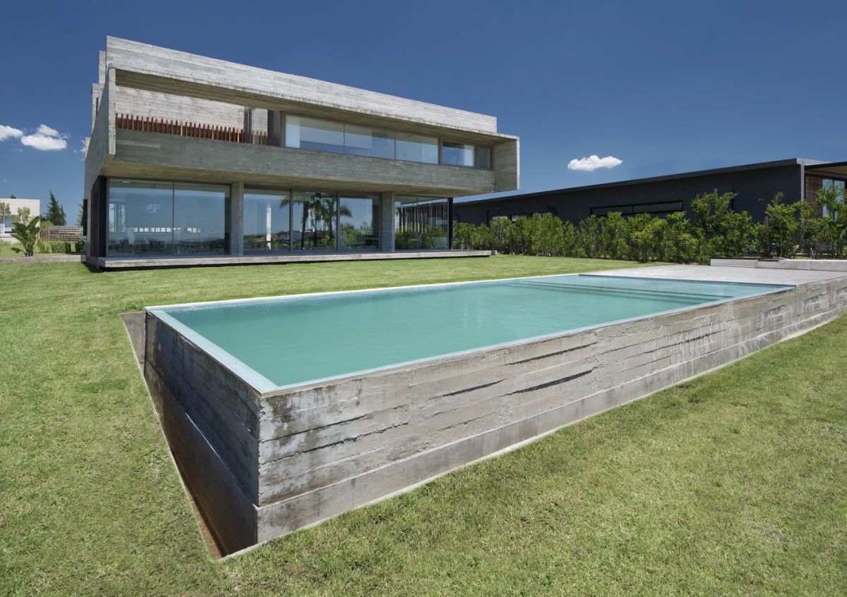 The swimming pool is rectangular and encased in concrete, just like the house