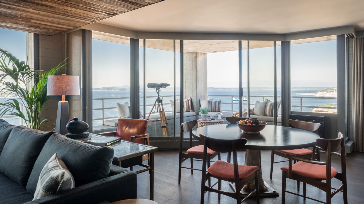 The dining area is framed by a curved balcony with a panoramic coastal view
