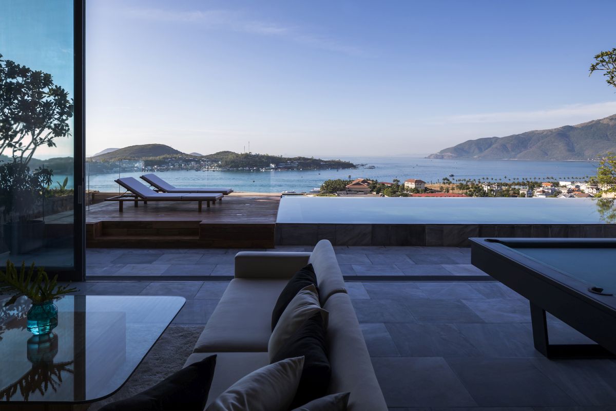 The living area is seamlessly extending outside towards the pool and the raised wooden deck