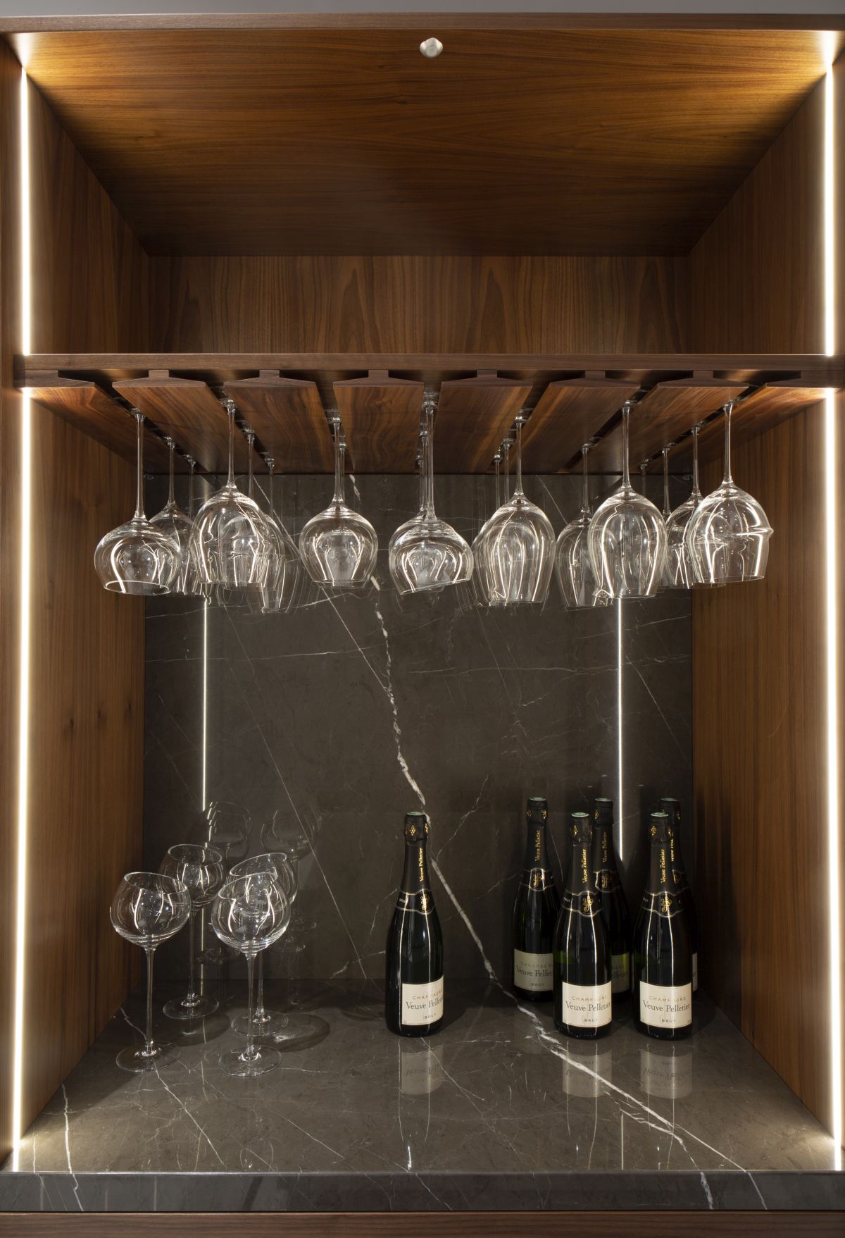 An elegant glass holding rack is seamlessly integrated into the bar unit, adding function without complicating the aesthetic