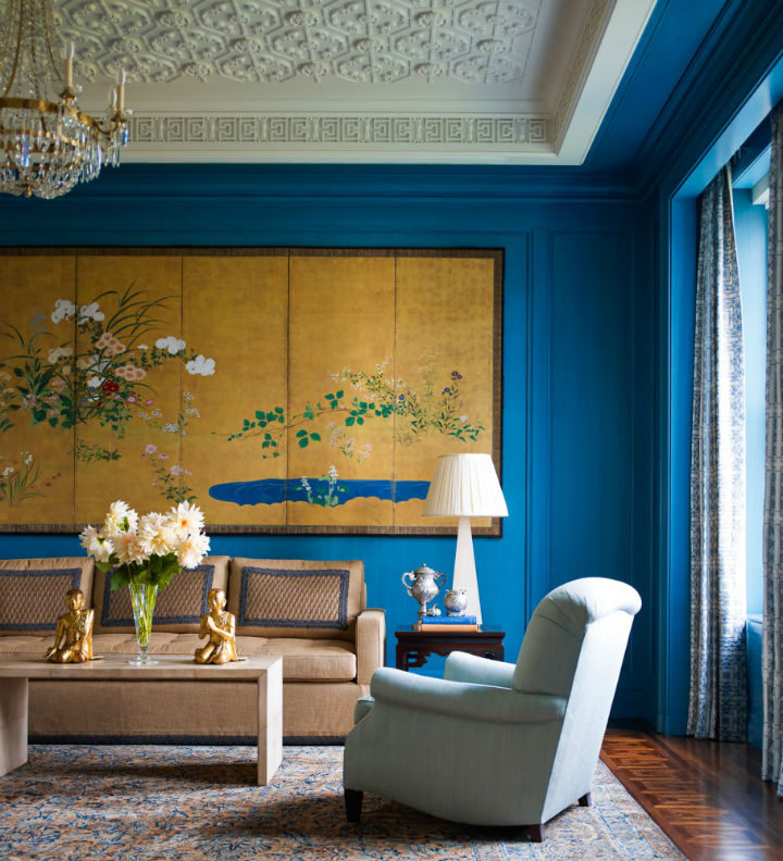 traditional living room with blue walls and large art above sofa