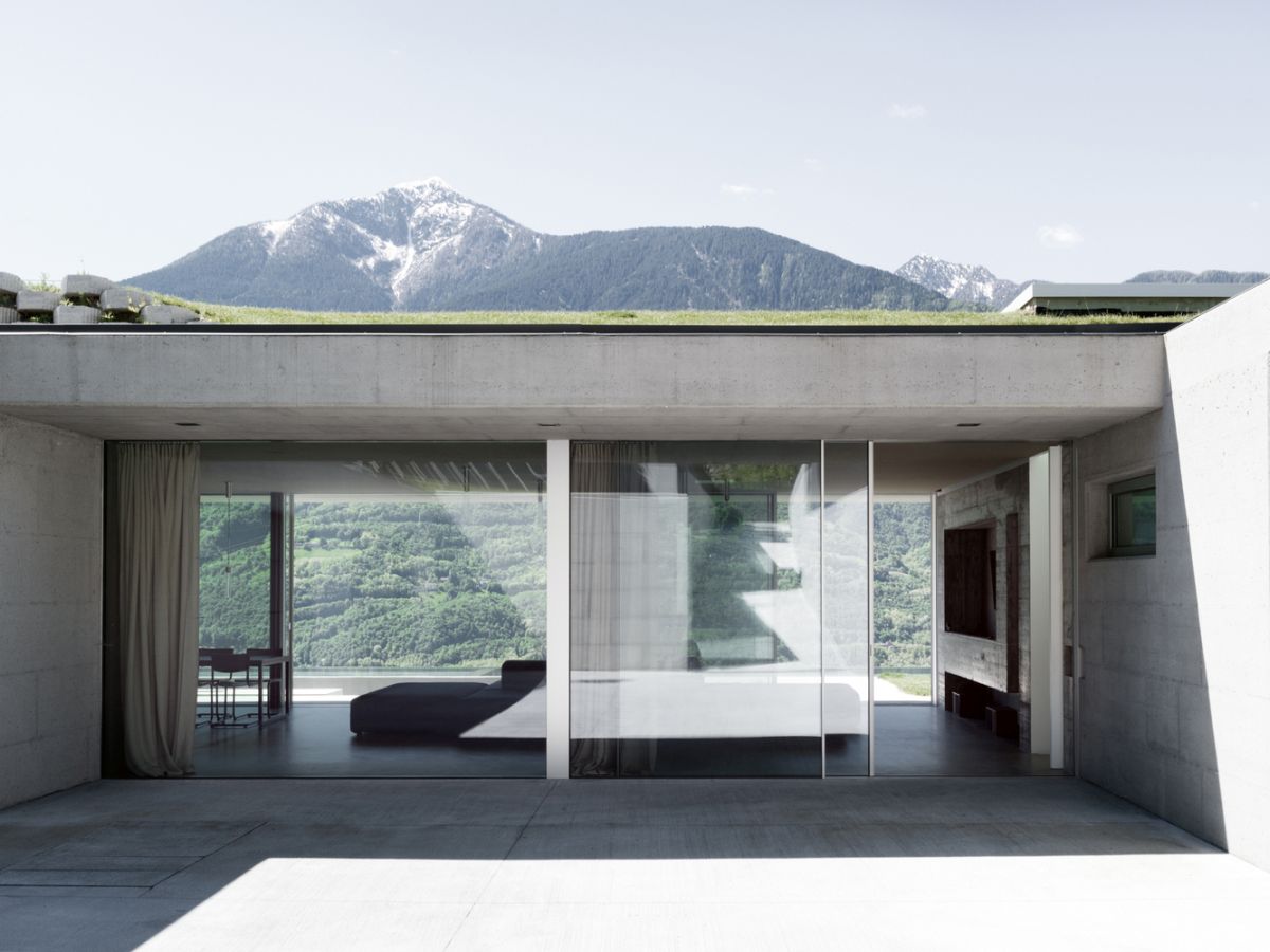 The . large glazed surfaces and the green roof combined with a simple concrete shell help the house become one with the land