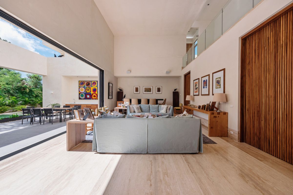 The central volume of the house has a high ceiling and large sliding doors facing the terrace and garden