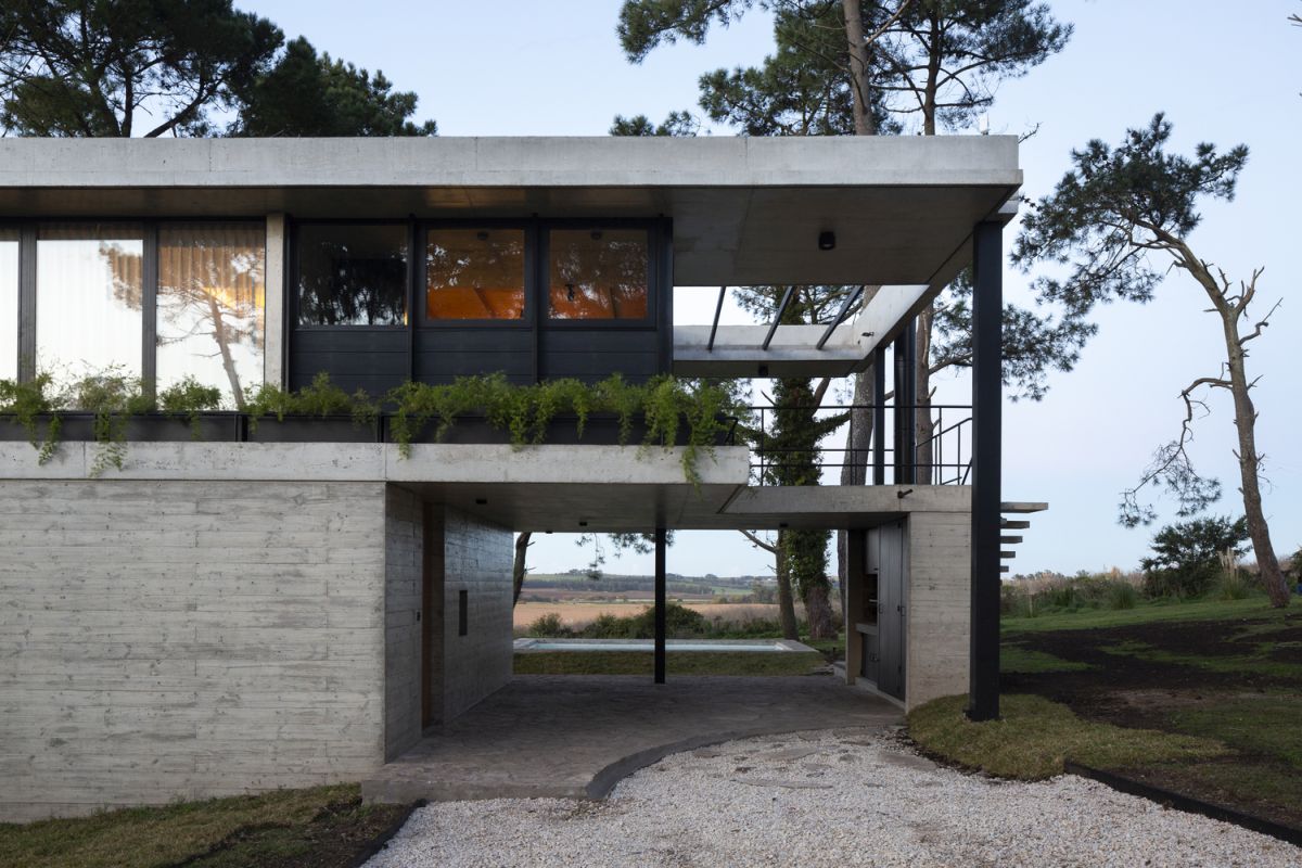 The upper floor is partially cantilevered over the concrete base which gives it a lightweight appearance