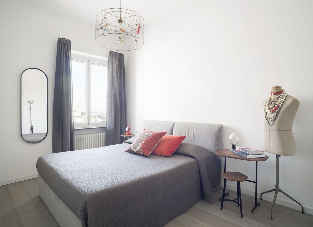 This bedroom is simple and has a delicate and feminine vibe, featuring soft greys and red accents