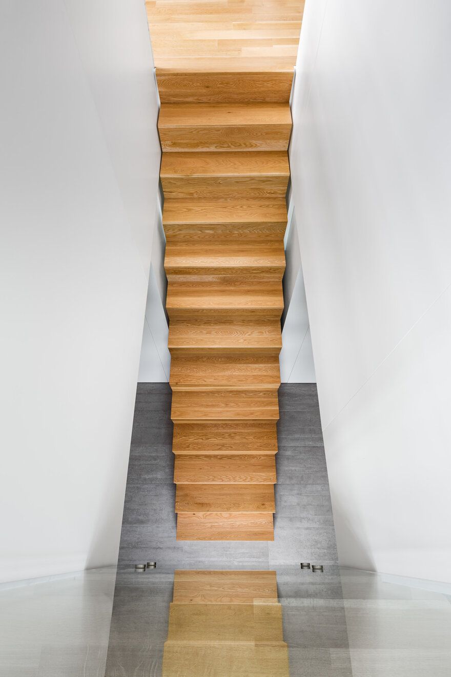 The social areas clustered on the ground floor and the private areas upstairs are connected by this simple wooden staircase