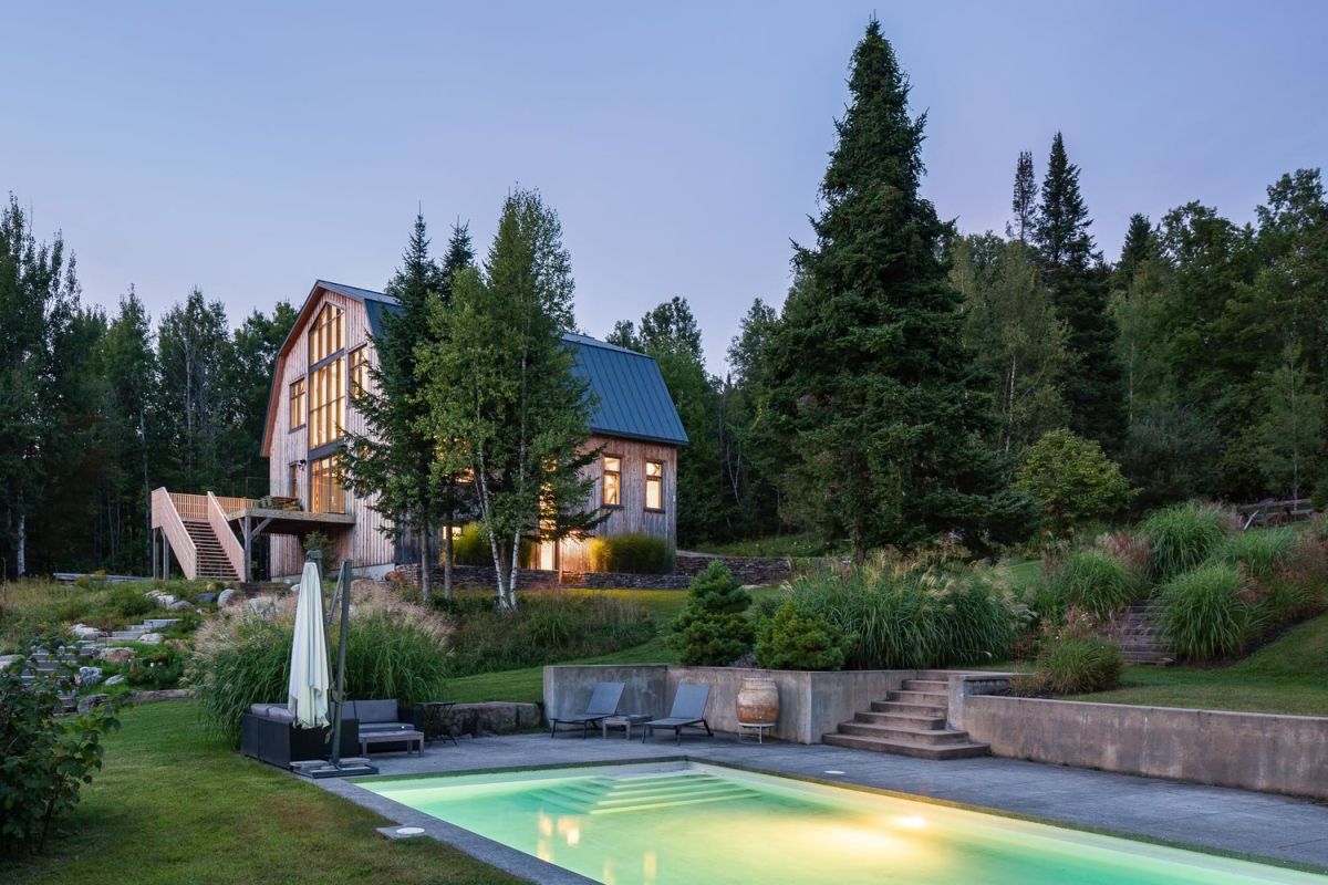 The barn, now a modern house, is surrounded by tall trees and lots of greenery