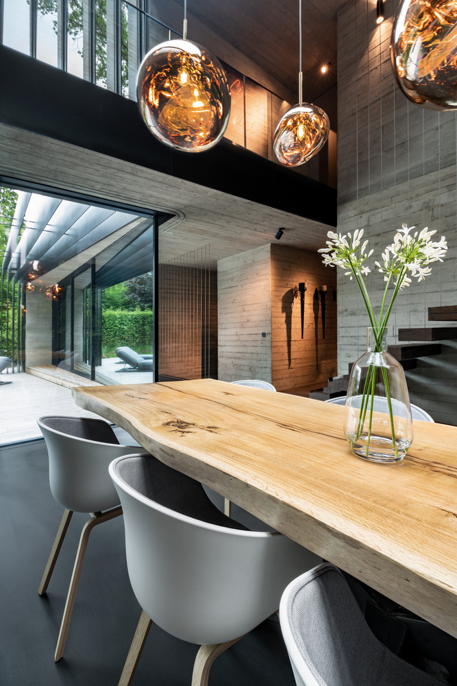 The live edge dining table softens the harsh exposed concrete surfaces, adding warmth to the ground floor