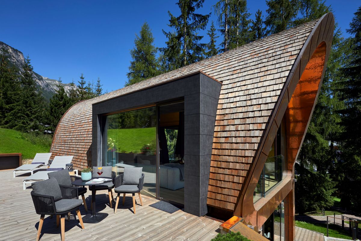 The curved facade is interrupted by a large opening on the side which connects the interior spaces to a wooden deck