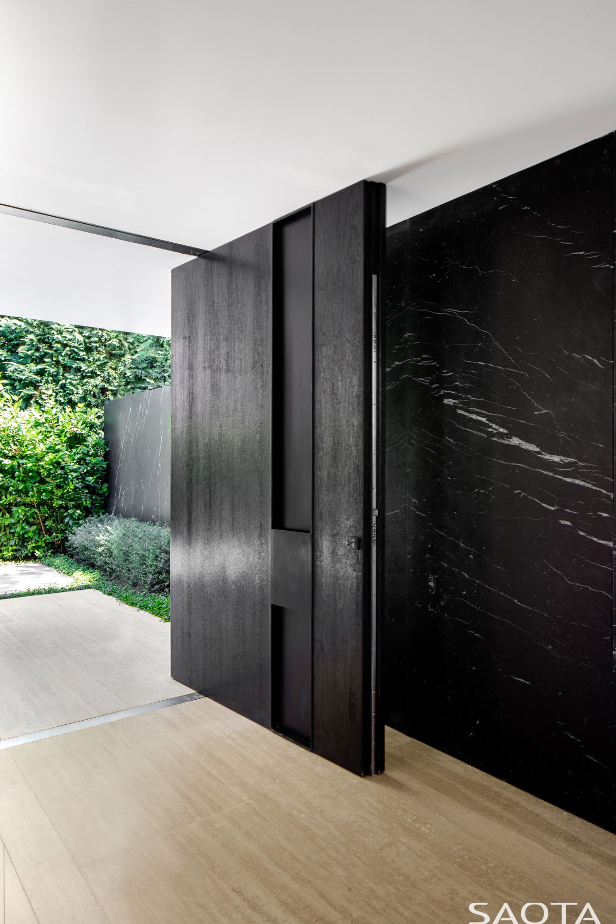 The main entrance is defined by a large and solid pivot door which contrasts with the white walls around it
