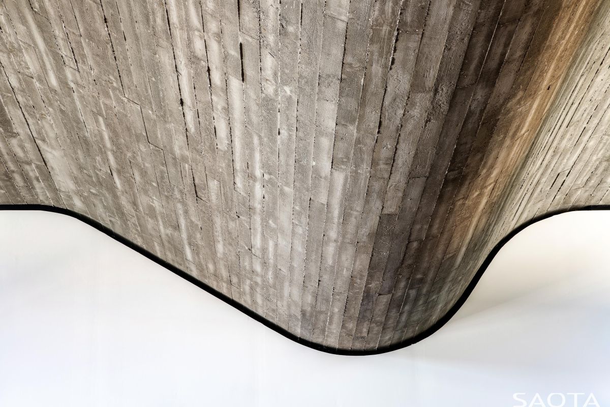 A closeup view of the undulating roof reveals the raw beauty of the wooden planks